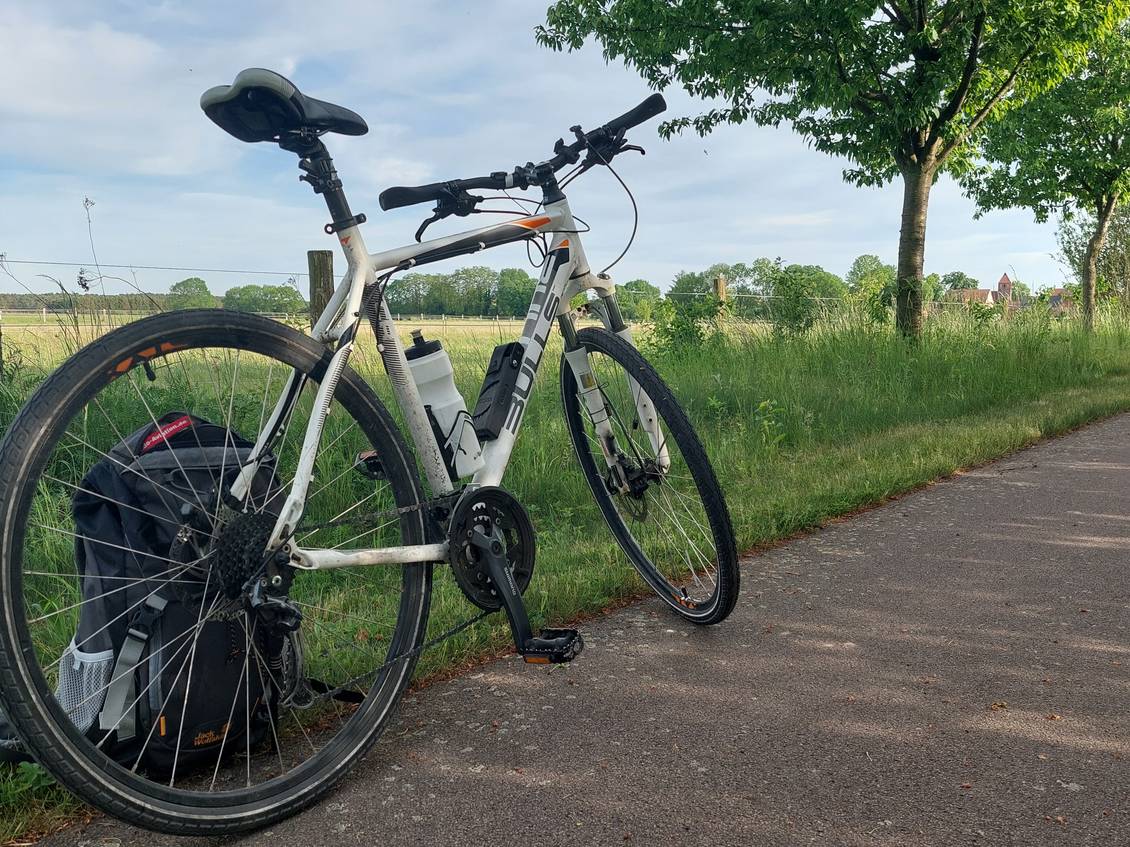 Das Foto zeigt ein abgestelltes Rad am Rand eines Radweges.