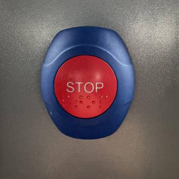Das Foto zeigt einen blauen Schalter mit einem roten Knopf, auf dem "Stop" steht.