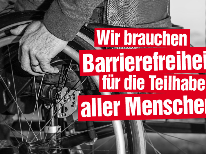 Das Foto zeigt in der Nahaufnahme einen Rollstuhl und die Hand einer älteren Person. Auf das Foto ist der Text "Wir brauchen Barrierefreiheit für die Teilhabe aller Menschen!".