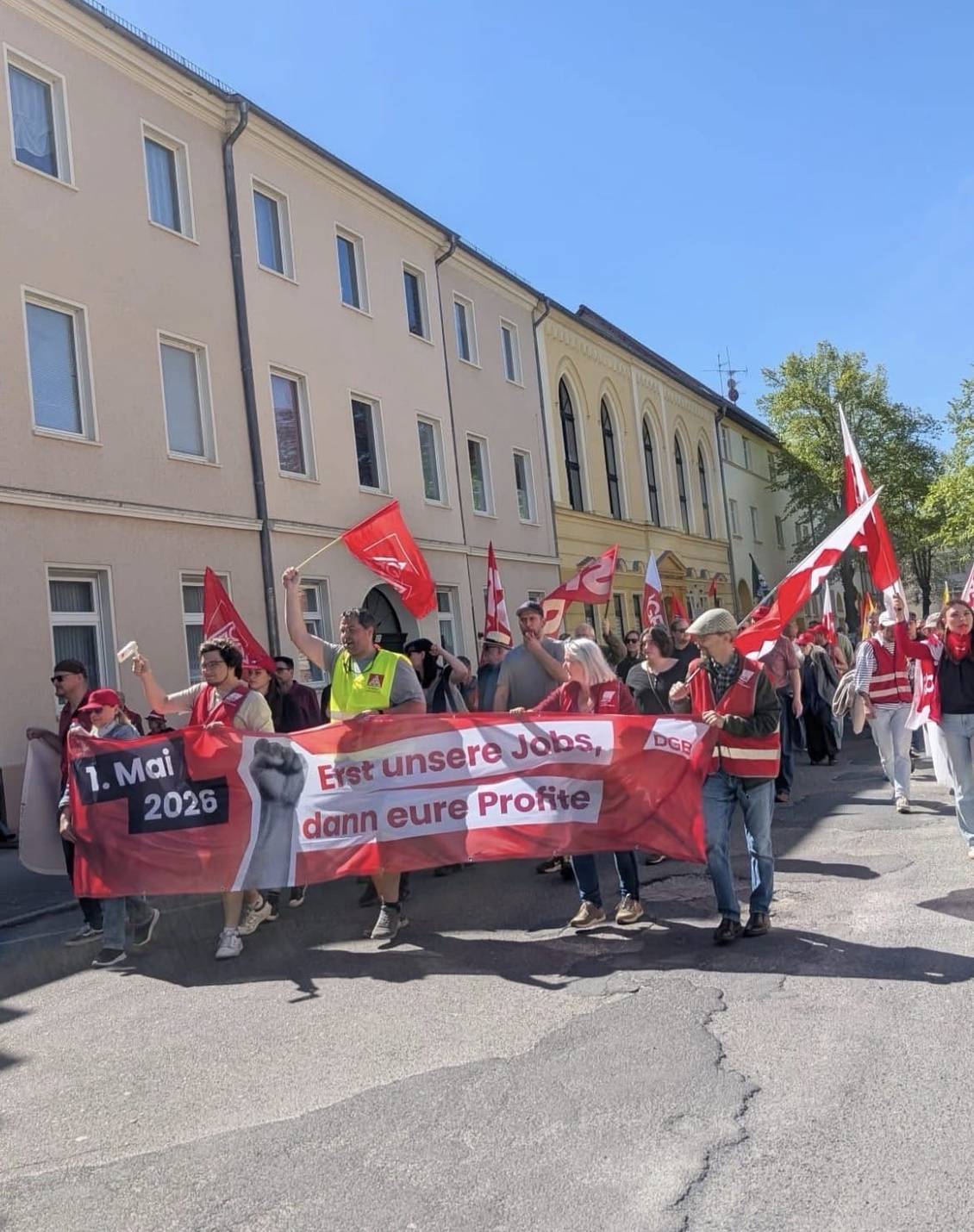 Das Foto zeigt eine Gruppe von Menschen, die Fahnen und Banner tragen.