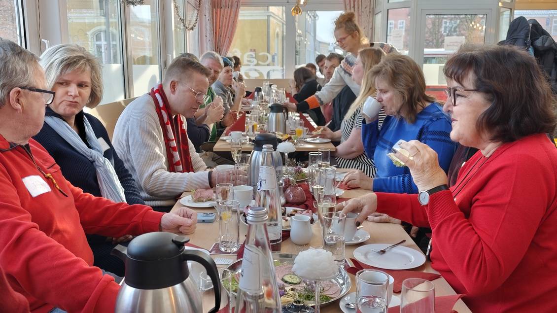 Das Foto zeigt mehrere Personen essend an einem langen Tisch.