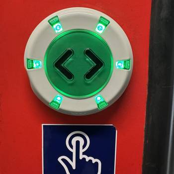 Das Foto zeigt einen grün leuchtenden Türöffner-Knopf in einem Zug.