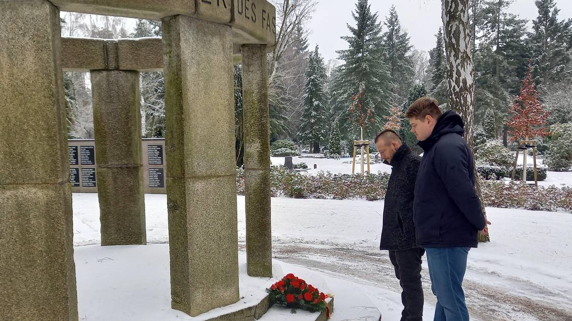 Das Foto zeigt zwei Personen vor dem Mahnmal auf dem Friedhof in Ludwigsfelde.