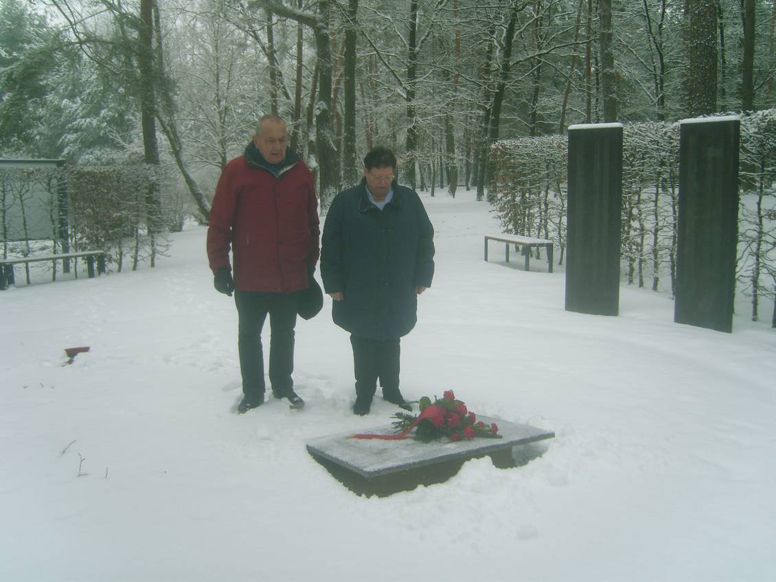 Das Foto zeigt zwei Personen vor der Gedenkplatte auf dem Friedhof.