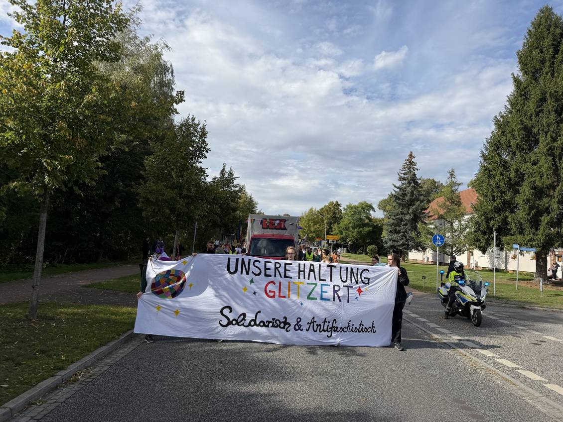 Das Foto zeigt ein Gruppe von Menschen, die ein Transparent tragen.