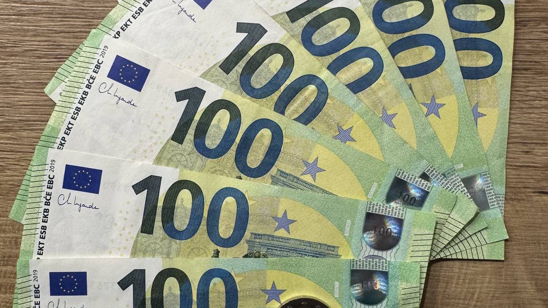 Das Foto zeigt eine Reihe von 100 Euro-Banknoten sowie 2 Euro-Münzen.