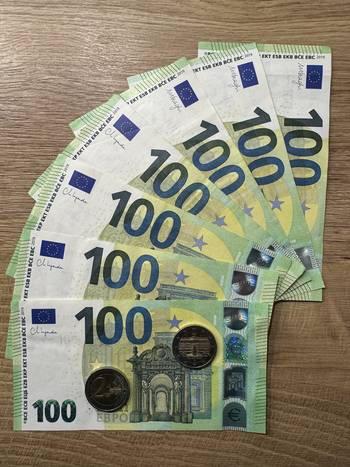 Das Foto zeigt eine Reihe von 100 Euro-Banknoten sowie 2 Euro-Münzen.