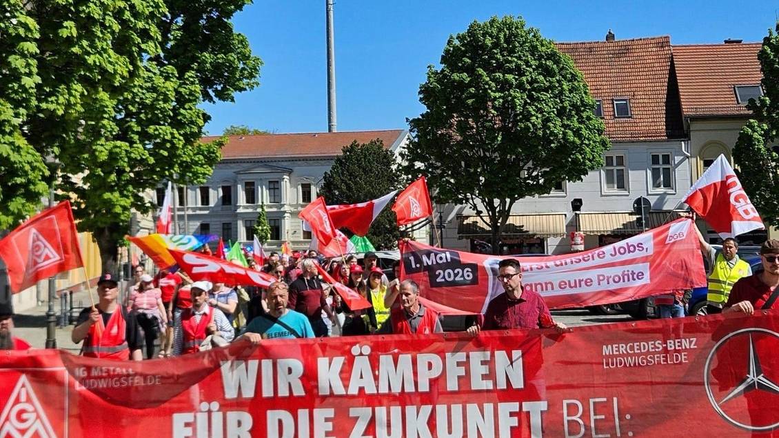 Das Foto zeigt viele Personen bei einer Demo. Einige tragen Fahnen und Banner.