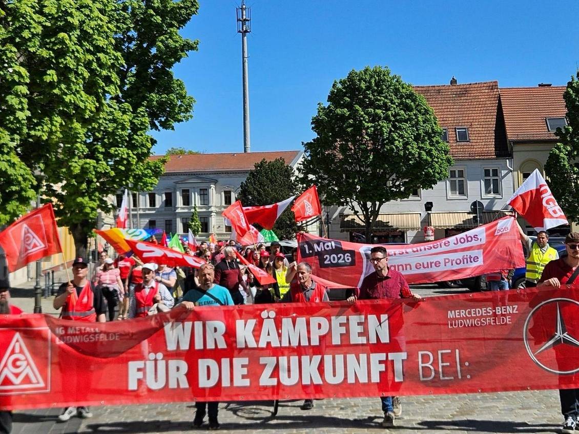 Das Foto zeigt viele Personen bei einer Demo. Einige tragen Fahnen und Banner.