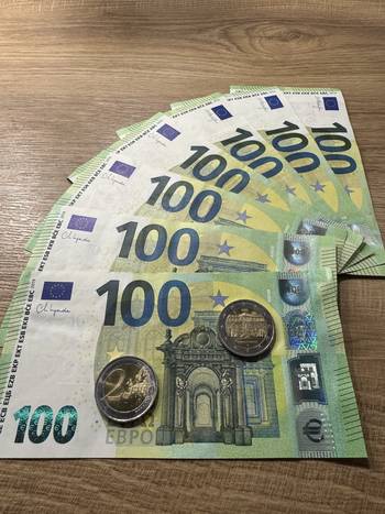 Das Foto zeigt eine Reihe von 100 Euro-Banknoten sowie 2 Euro-Münzen.