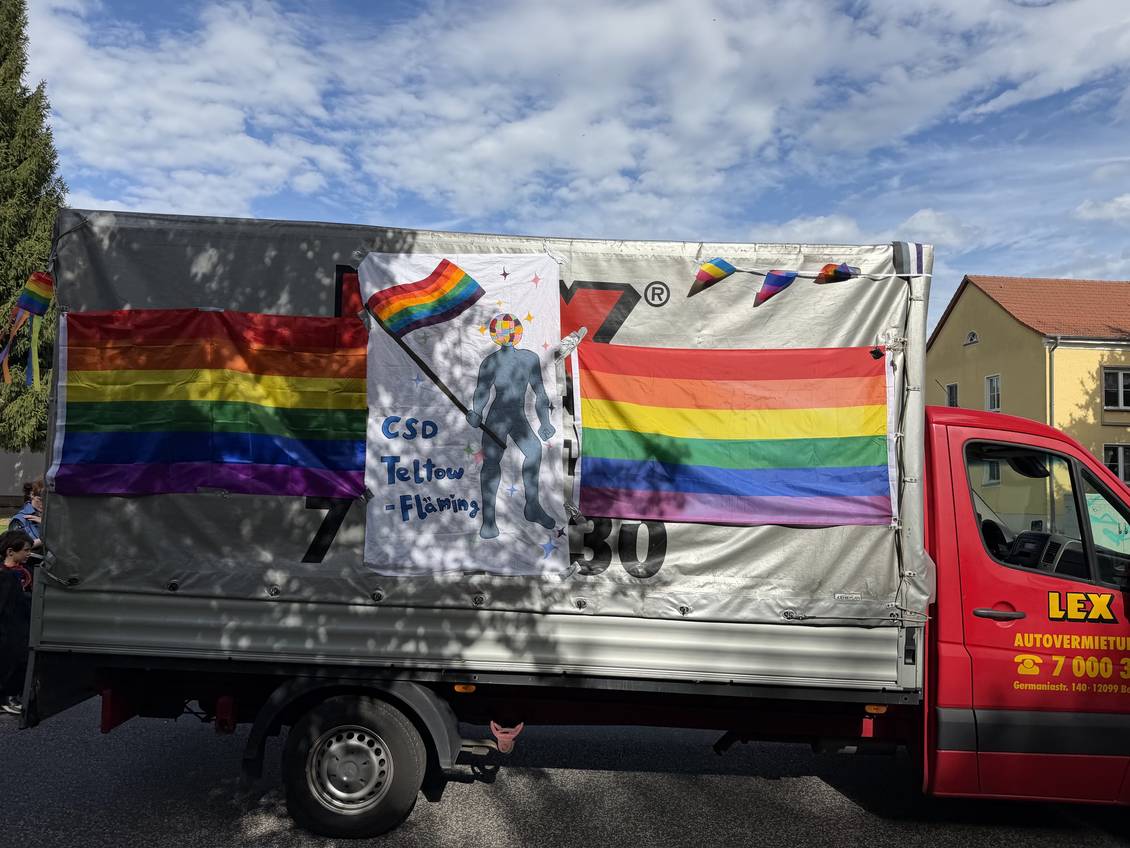 Das Foto zeigt einen Transporter mit Regenbogenfahnen.